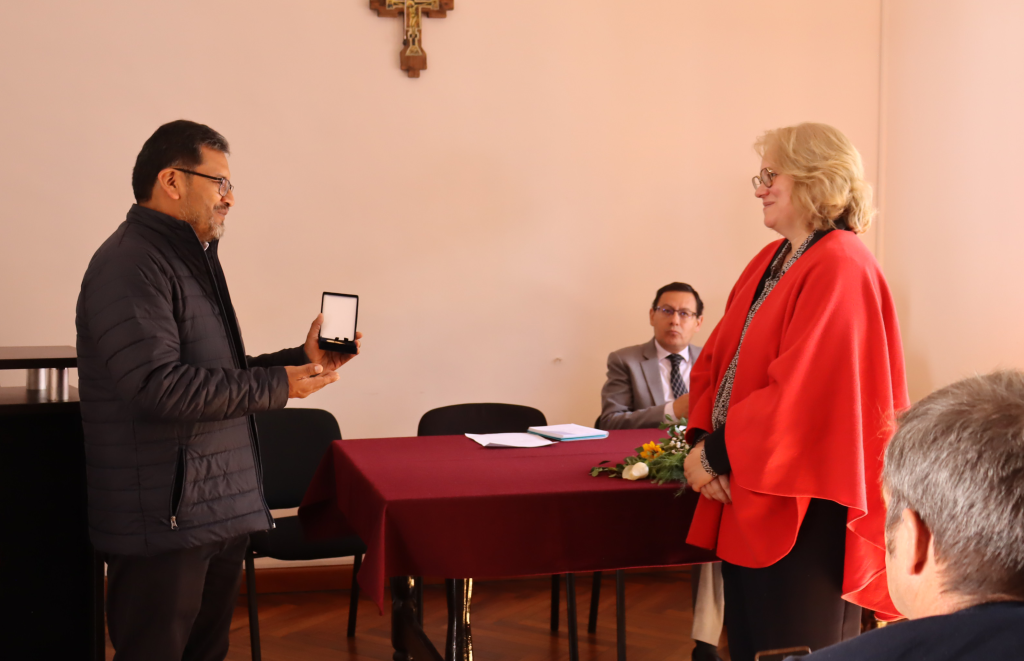 El presidente del directorio del OSC, padre Freddy Quilo, S.J., entrega el reconocimiento a la embajadora de Francia en Bolivia, Helene Roos. Foto: ANF